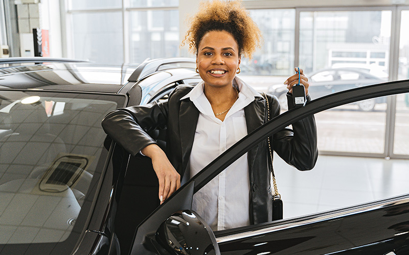 Mulher comemorando com a chave do carro novo
